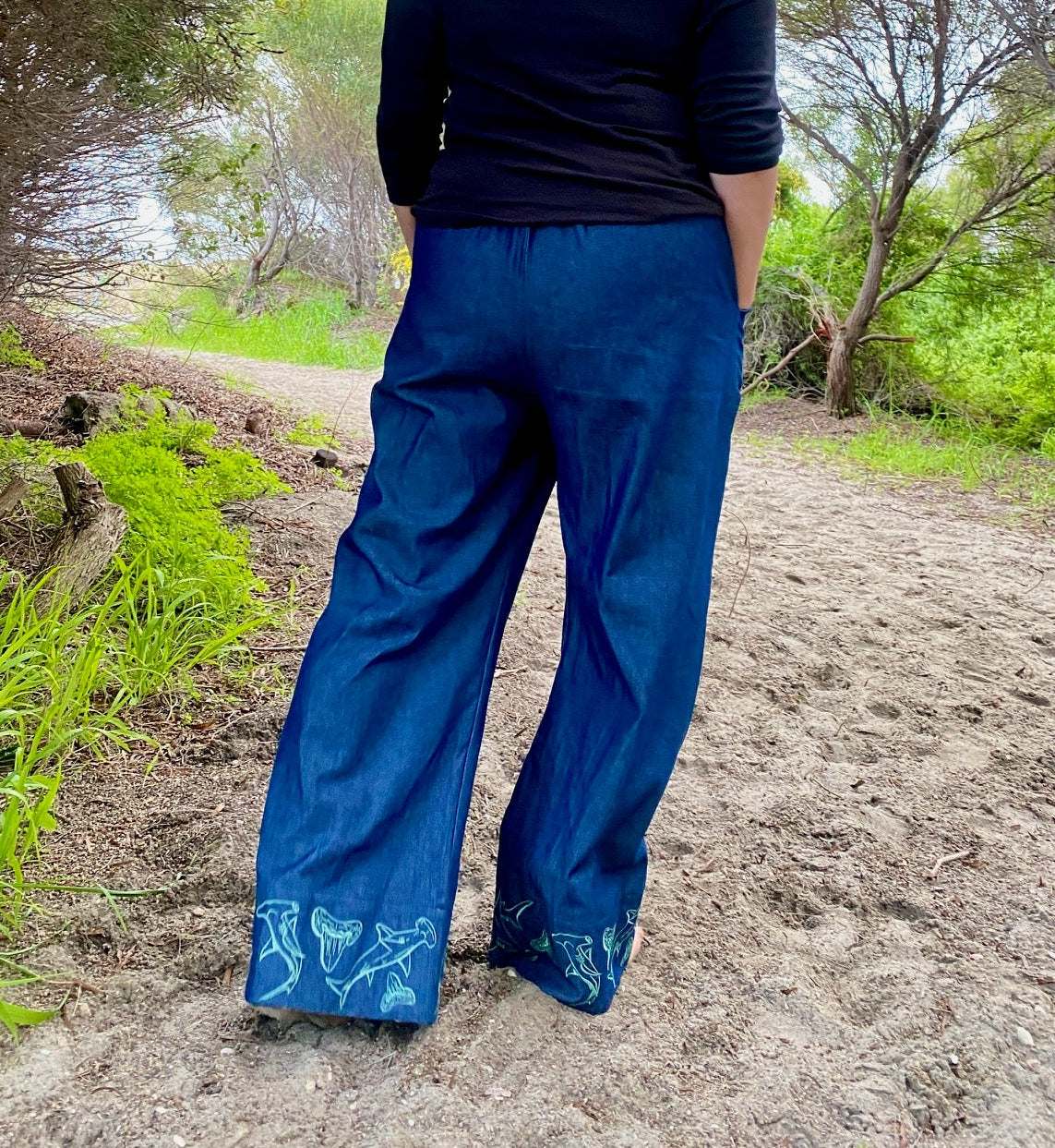 Women's wide-leg beach pants with a tie waist and hammerhead shark motif embroidered cuffs and generous pockets.