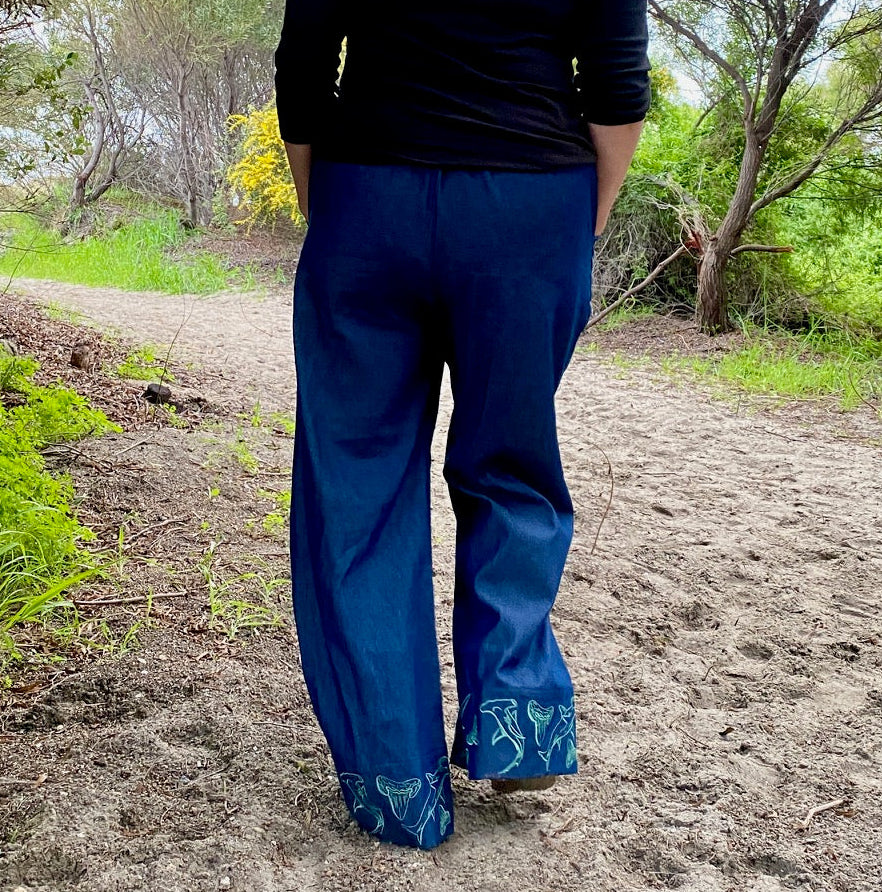 Women's wide-leg beach pants with a tie waist and hammerhead shark motif embroidered cuffs and generous pockets.