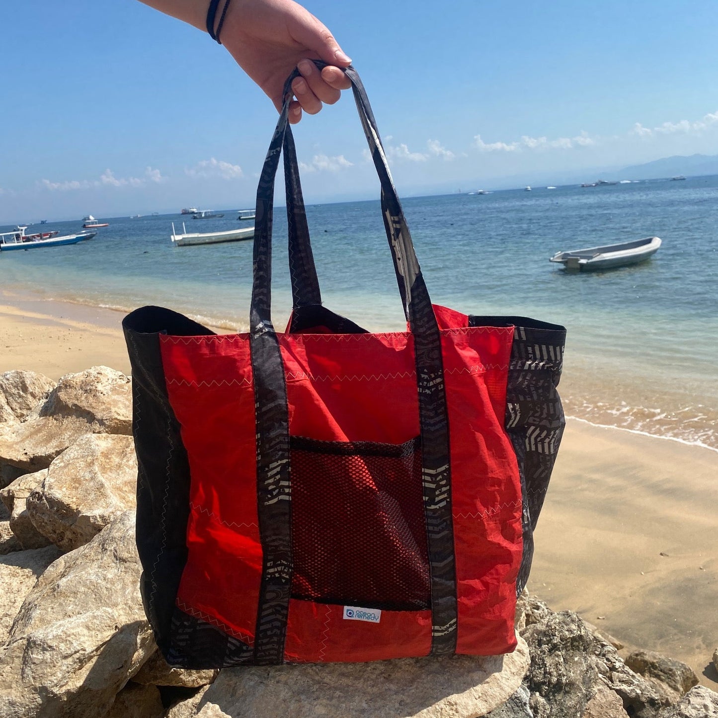 A red and black tote bag made from an upcycled kite surfing kit. Mesh pocket on the outside, binding on the seams, made to last and last.